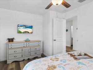 a bedroom with a bed with a dresser and a ceiling fan at Beach and Boaters Delight! in Fort Myers Beach