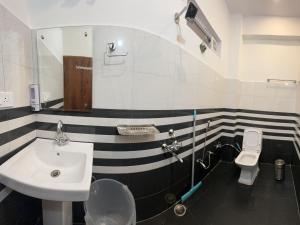 a black and white bathroom with a sink and a toilet at Hotel Kedarkhand in Sonprayag