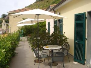 eine Terrasse mit einem Tisch, Stühlen und Sonnenschirmen in der Unterkunft Hotel Del Sole in Riomaggiore