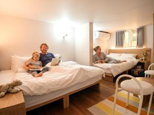 a man and a child sitting on a bed with a laptop at Hotel Soda STAY in Seoul