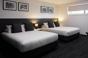 a hotel room with two beds and a window at Settlers Inn in Port Macquarie