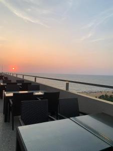 a patio with tables and chairs and the ocean at sunset at Azure Luxury Apartment Luxury Stay Near Airport Negombo in Negombo