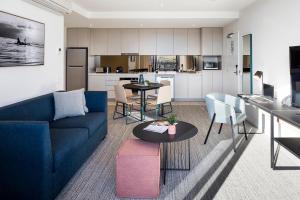 a living room with a blue couch and a table at Quest Robina in Gold Coast