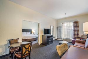 a hotel room with a bed and a living room at Clarion Inn & Suites Central Clearwater Beach in Clearwater