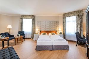 a hotel room with a large bed and chairs at Hotel Kaiserhof Eisenach in Eisenach +46 photos