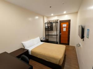 a small room with a bed and a television at Top Star Hotel Manaoag in Manaoag