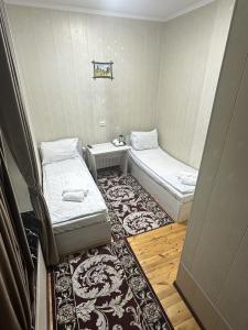 a small room with two beds and a rug at Bilol Guest House in Samarkand