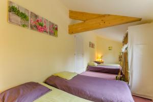two beds in a room with purple sheets at L'olifred in Mathaux
