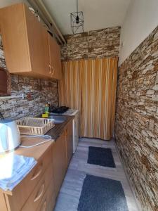 a kitchen with wooden cabinets and a brick wall at Konak kod Daće in Drvar