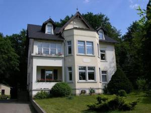 ein großes weißes Haus mit einer Veranda und Fenstern in der Unterkunft Hotel-Pension Königswald in Dresden