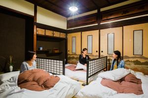 three women sitting on beds in a room at Guest House Kura in Suzaka