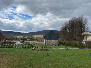 a barn in a field with a white truck in the background at Mountain View Home in Wysowa-Zdrój