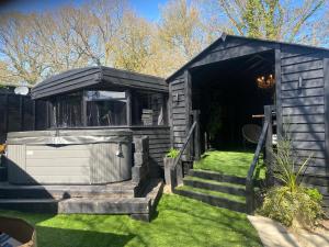 a black shed with stairs leading into a yard at Simons Whody Hideaway in Ulcombe