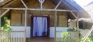 a building with a door with a blue curtain at Bungalow Frédéric in Hell-Ville