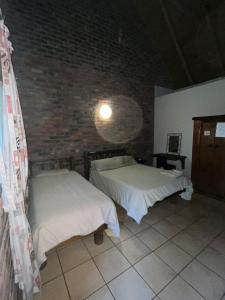 two beds in a room with a brick wall at Lapa Lê Lê Lodge in Ellisras