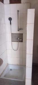 a shower in a white tiled bathroom at Bungalow Frédéric in Hell-Ville