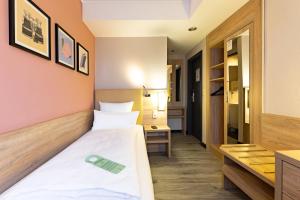 a small room with a bed and a desk at Garner Hotel Bremen North by IHG in Bremen +109 photos