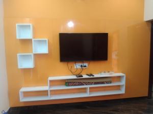 a tv on a wall with a white entertainment center at Peter's villa in Kuttālam
