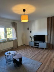 a living room with a flat screen tv and a table at Ferienwohnung Eifelhirsch in Ettringen