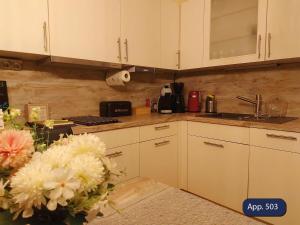 a kitchen with white cabinets and flowers on the counter at Fewo Eisvogelnest in Sankt Englmar