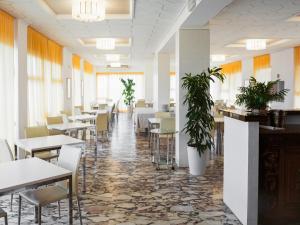 a dining room with tables and chairs and plants at Hotel Metropol in Pesaro