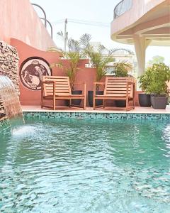 a swimming pool with two chairs and a fountain at Zumi Stays in Udaipur