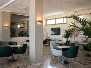 un restaurante con mesas, sillas y TV en Hotel Metropol, en Pesaro