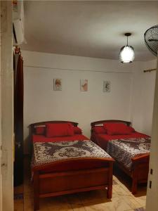two beds in a room with red pillows at شالية بقرية ريم الفلا in Dawwār Shindī Fannūsh