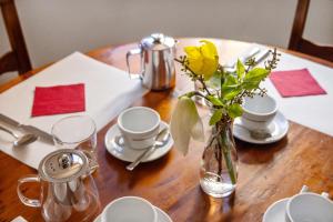 a wooden table with a vase with yellow flowers in it at Ecovillage Sanctuary Bordei in Palagnedra +10 photos