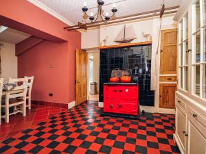 a kitchen with a red cabinet and a checkered floor at Captain's House in Morfa Nefyn