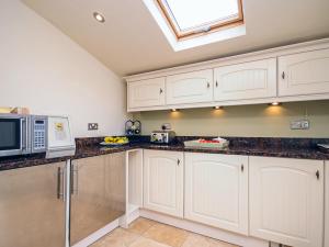 a kitchen with white cabinets and a skylight at Captain's House in Morfa Nefyn