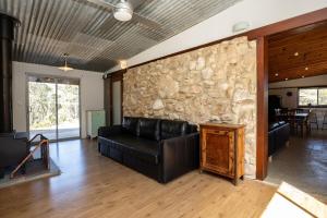 a living room with a stone wall and a black leather couch at Stony Rise Ranch in Pelican Lagoon