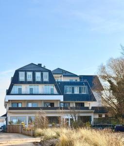 a large white house with a black roof at Hotel Haus am See in Lembruch
