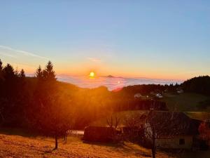 a sunset with the sun setting over the ocean at HolidayHouse Mahova koča in Zreče