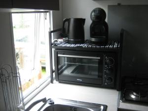a microwave in a kitchen with a coffee maker on top of it at erick in Angles