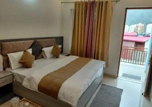 a bedroom with a large bed and a balcony at Hotel Kedarkhand in Sonprayag