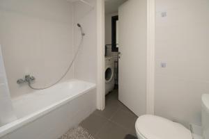 a white bathroom with a tub and a toilet at Assuta family in Tel Aviv +61 photos
