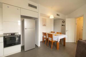 a kitchen with a table with chairs and a refrigerator at Assuta family in Tel Aviv