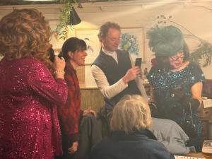 a group of people standing around a woman looking at a cell phone at The loft in Cirencester