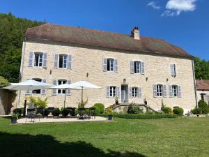 a large brick building with tables and umbrellas at La SAURA in Lusigny-sur-Ouche