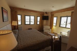 a bedroom with a bed and a couch and windows at Hualcupen Complejo in Copahue