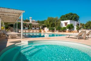 a swimming pool with chairs and a house at Masseria Salinola in Ostuni