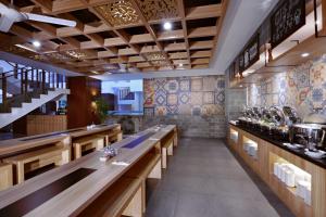 a dining room with wooden tables and tile walls at Fame Hotel Sunset Road in Kuta