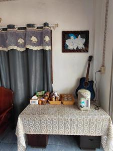 a table in a room with curtains and a guitar at Khopchai Guesthouse in Ban Houayxay