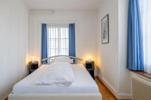 a bedroom with a bed with blue curtains and a window at Hotel Altstadt in Erlach