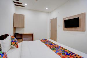 a bedroom with a bed and a tv on the wall at FabHotel Swastik Villa in Varanasi