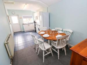 a kitchen and dining room with a wooden table and chairs at Graig Goch in Burry Port