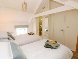 a white bedroom with two beds and a bathroom at Graig Goch in Burry Port