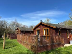 a wooden house with a fence in the yard at 2 Riverside Lodge in Cenarth