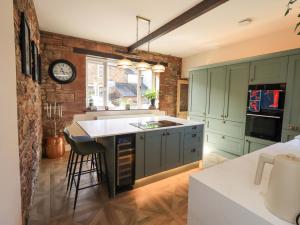 a kitchen with green cabinets and a clock on the wall at Yew Tree Cottage in Wigton